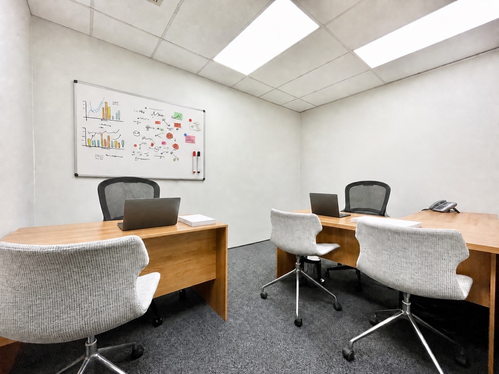 Twin office with two desks, visitor chairs and a whiteboard